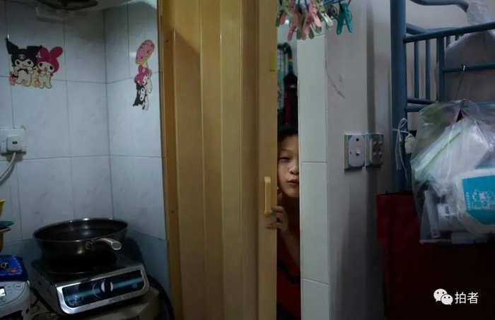 ▲黄凤儿子调皮地从门缝里探出脑袋，家里墙上到处是他的卡通贴纸。