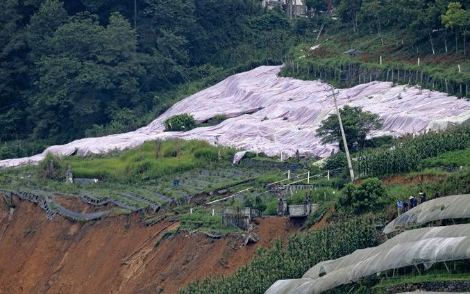 7月23日，工作人员在滑坡地段上方铺上油布，防止出现新的滑坡。新京报记者 陶冉摄