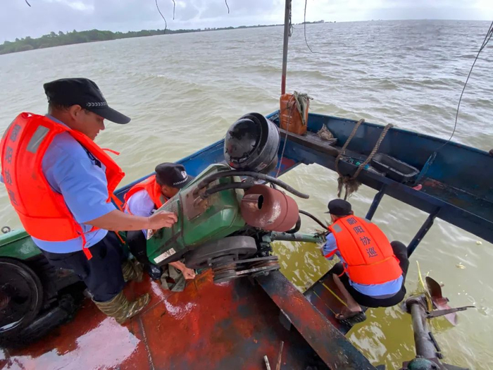 ▲在鄱阳湖面巡护时，船尾的发动机螺旋桨时常被缠住，需要用刀割开。新京报记者 杜雯雯 摄