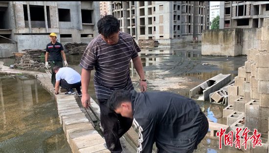 业主们在积水严重的空地上铺起小路。