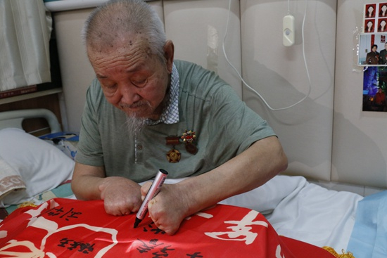 　　志愿军老兵崔洪锡在“志愿军老兵帮扶计划”旗帜上签名。袁燕利/摄