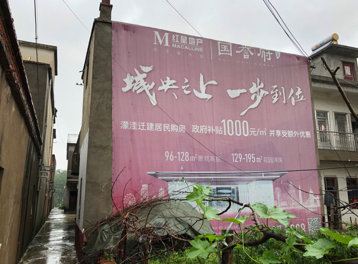 ▲老观乡村里，挂着迁建居民购房广告。新京报记者解蕾摄 