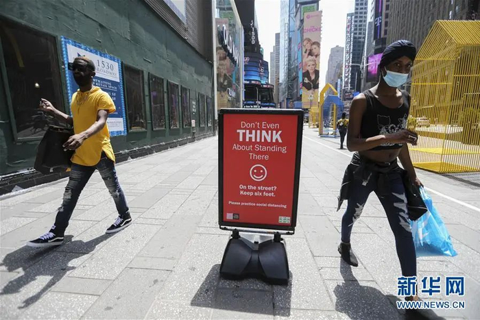 ▲7月23日，在美国纽约时报广场，人们从保持社交距离的提示牌旁走过。（新华社记者 王迎 摄）
