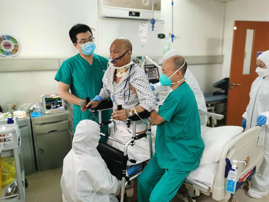 肺移植术后，医护人员帮助崔志强站立训练。图中左一为李光。武汉大学人民医院供图