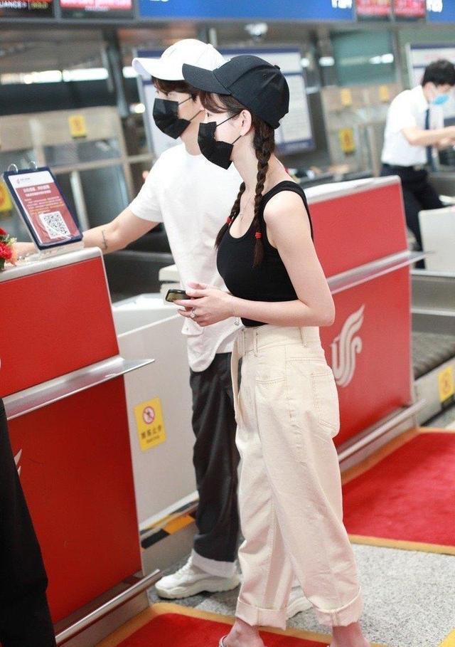 张檬机场私服穿搭，黑色吊带背心搭配一条米白色阔腿裤，休闲随性