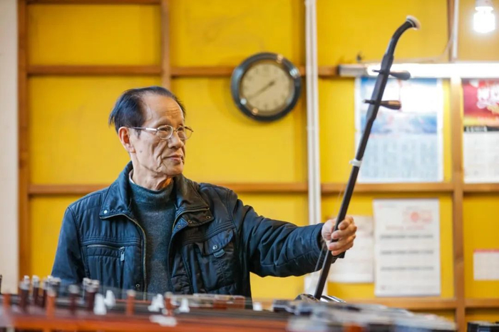 琴坊里，万其兴检验即将出厂的二胡。梅村街道供图