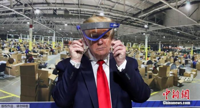 资料图：美国总统特朗普手举防护面具。