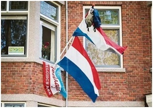 荷兰家庭在家门口竖起国旗挂上书包以庆祝孩子通过高中毕业考试。资料图片