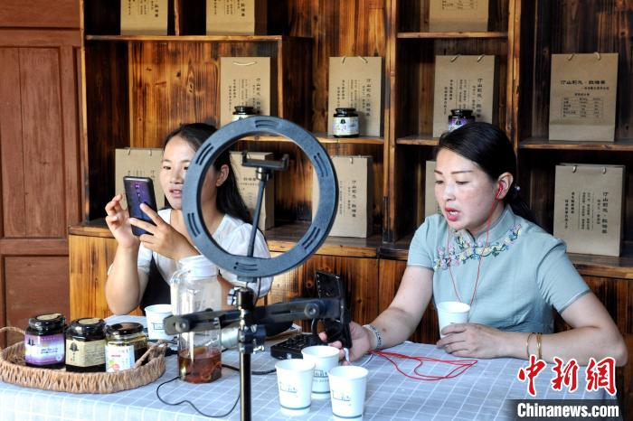 在“红军街”上的商铺，店主正在电商直播售卖特色农副产品。　龚雯 摄