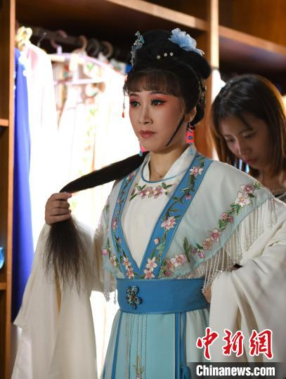 图为一名服装老师在给越剧演员陈丽整理戏服。　张茵 摄