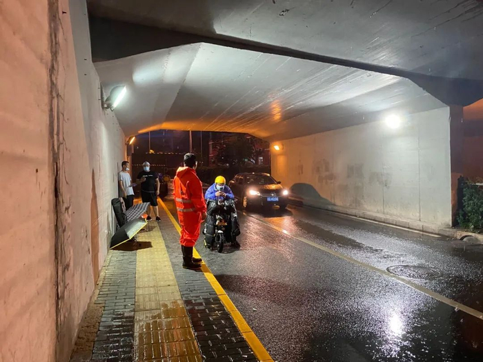 ▲张道平在夕照寺铁路桥下与躲雨的外卖小哥交流。新京报记者肖薇薇 摄