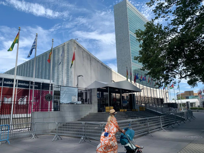 ▲2020年7月20日，一名推童车的女子经过位于纽约的联合国总部游客入口处。新华社记者 王建刚 摄