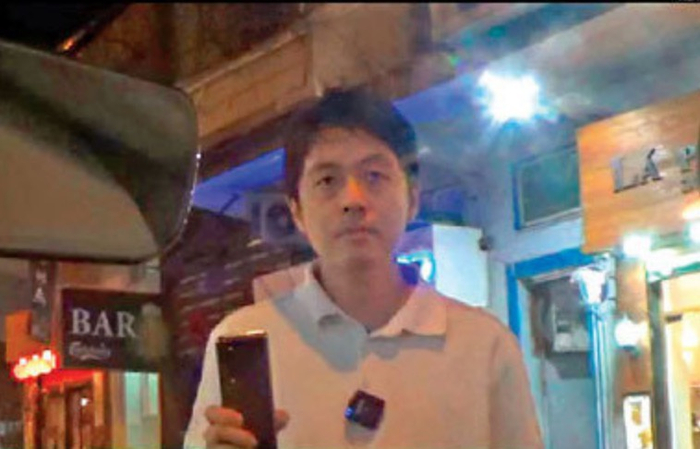 许智峰站在车头不断用手机拍摄车内记者