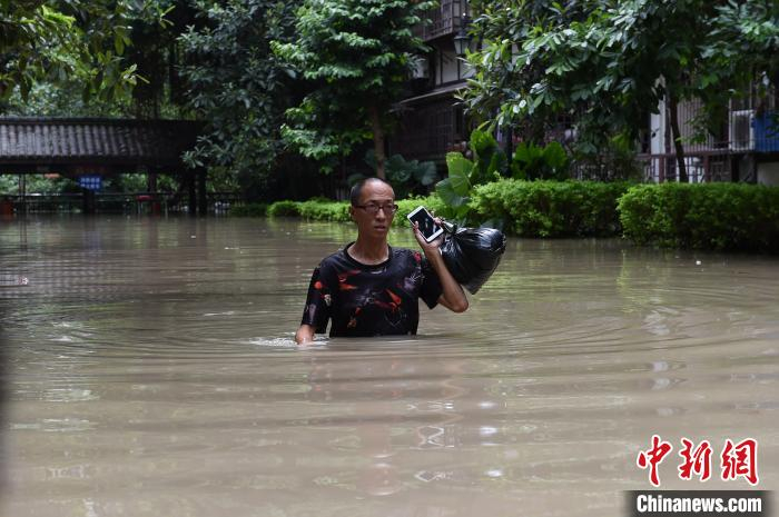 图为市民行走在洪水中。　周毅 摄
