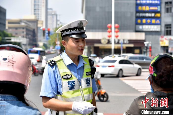 交警韩纪成劝导骑电车路人再热也需要配戴安全头盔。　朱志庚 摄