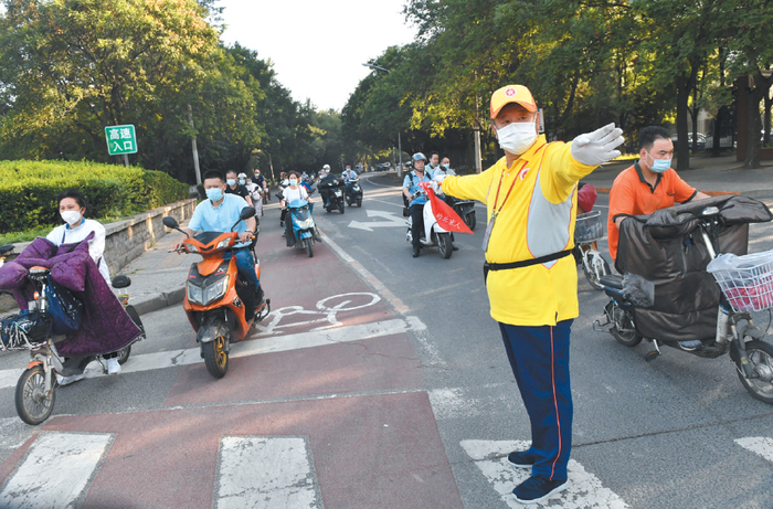 ▲8月14日，朝阳区首都机场辅路路口，文明引导员在绿灯亮起时用规范的手势引导骑行者通过。新京报记者 吴宁 摄