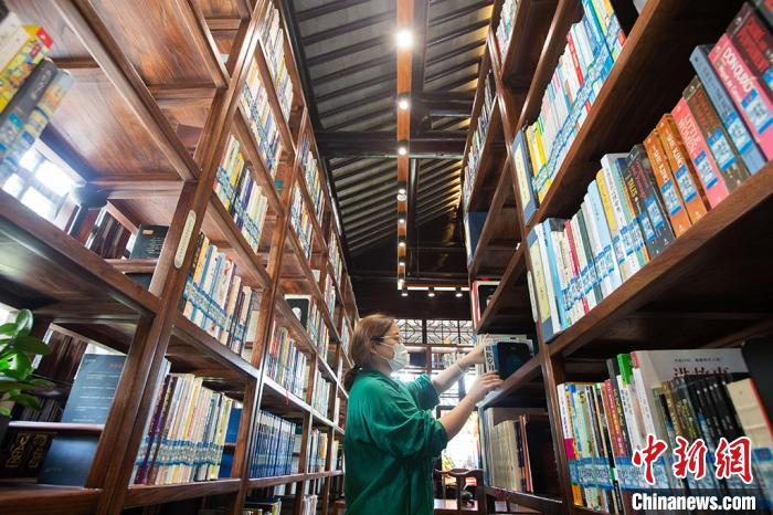 花桥24小时自助图书馆“世美书房”内，工作人员整理书籍。该书房位于花溪公园内，古色古香的屋檐下，周边环境优美，是花桥人民热衷的休闲赏景之地。　泱波 摄