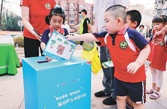 　　沈阳市兰妮幼儿园黎明园的小朋友们把图书和绘画卡放进捐赠箱中