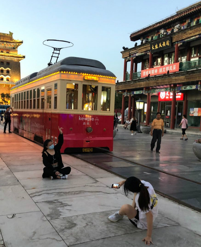 女孩坐在地上与铛铛车合影