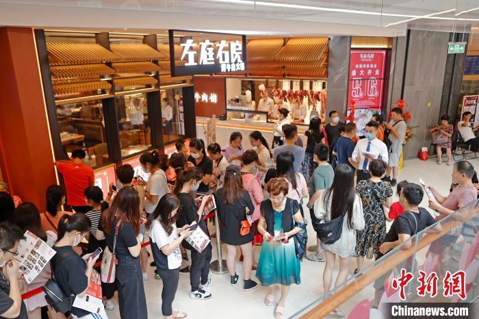 民众在餐饮商铺前排队等待。　殷立勤 摄