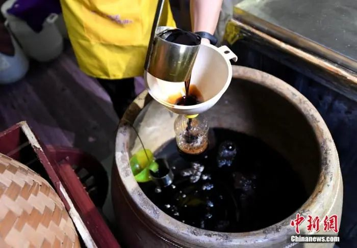 图为工人将做好的酱油进行罐装。王东明 摄