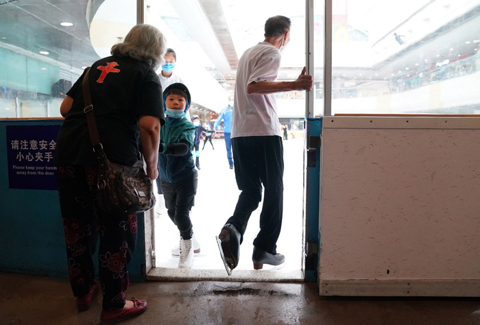 姬大爷穿上花滑鞋登上冰场，与他擦身而过的是刚刚结束滑冰练习的小朋友。