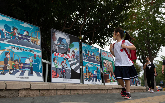 上地实验学校路口，交管部门设置了道路安全教育宣传牌，“新小一”的小朋友从旁边路过。摄影/新京报记者 李凯祥