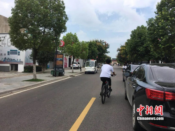 　　村中孩童骑车行在乡村道路上。吴兰/摄