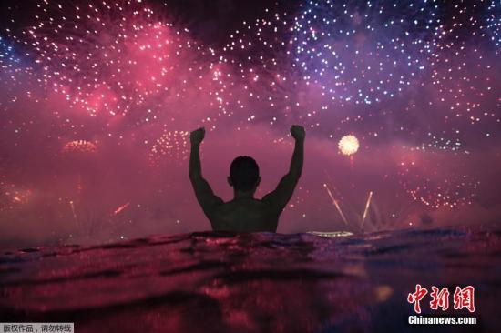 资料图：当地时间2019年1月1日凌晨，民众在水中观看巴西里约热内卢科帕卡巴纳海滩新年烟火表演。