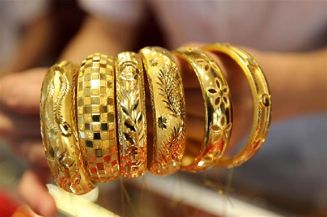 资料图：江苏连云港市赣榆区一家金店营业员在展示黄金饰品。（图片来源：视觉中国）