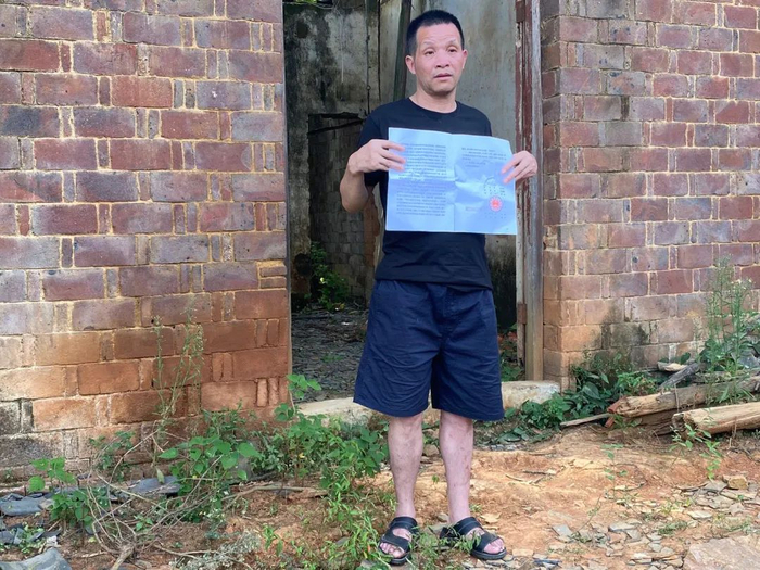 ▲张玉环拿着无罪的判决书与老宅合影。新京报记者 杜雯雯 摄