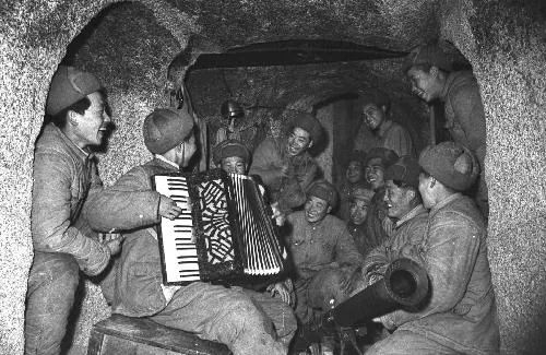 ▲战斗间隙，志愿军战士在防空洞里拉琴唱歌。（资料图片）