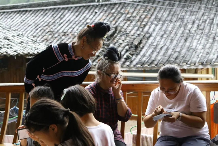 ▲季刀村龙飞力（左一）和其他绣娘教来自杭州的孩子和家长苗绣。受访者供图。