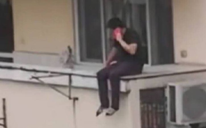犯罪嫌疑人坐在窗外平台上。网传视频截图