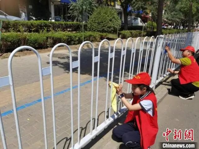 （图为兰州城关区的学生志愿者擦拭街头栏杆。城关区宣传部供图）