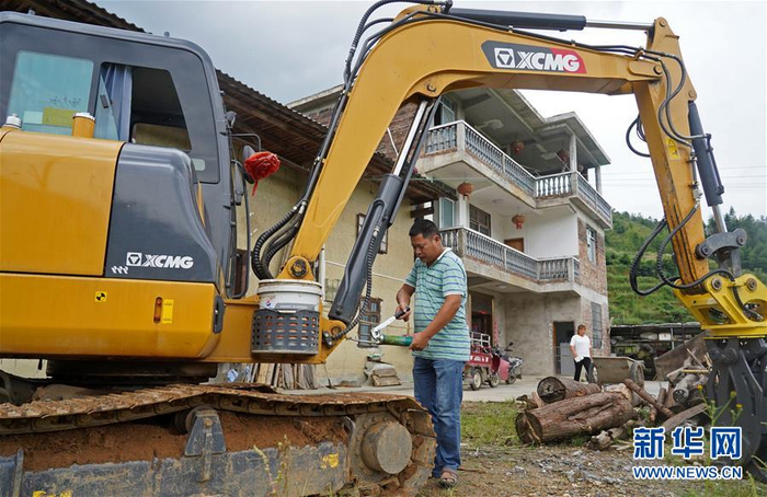 吴年有在家门前检修挖掘机，他在去年学会了驾驶挖掘机（9月10日摄）。新华社记者 万象 摄