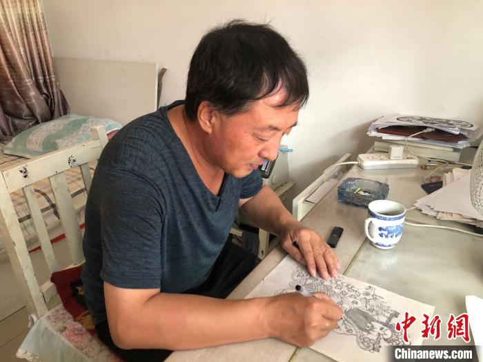 李宝峰在绘制剪纸图稿。　郝烨 摄