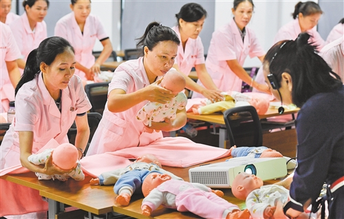 近日，在海南省儋州市的海南西部家庭服务中心，学员在老师的指导下练习婴儿包单。新华社记者 杨冠宇摄