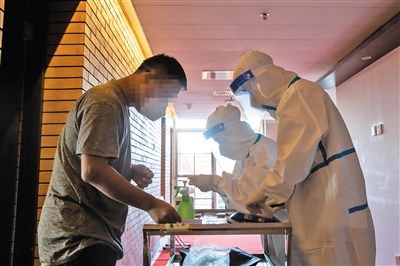 昨日，大兴区某集中观察酒店，工作人员逐门登记旅客详细信息。新京报记者 李凯祥 摄