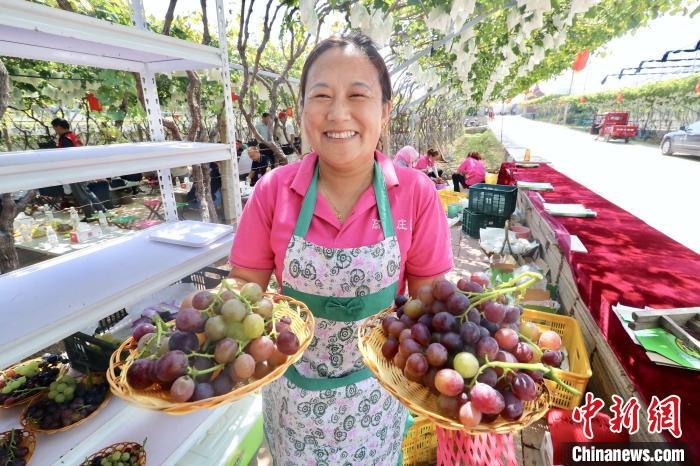 果农为游客端上刚刚采摘下来的新鲜葡萄。　孙科强 摄