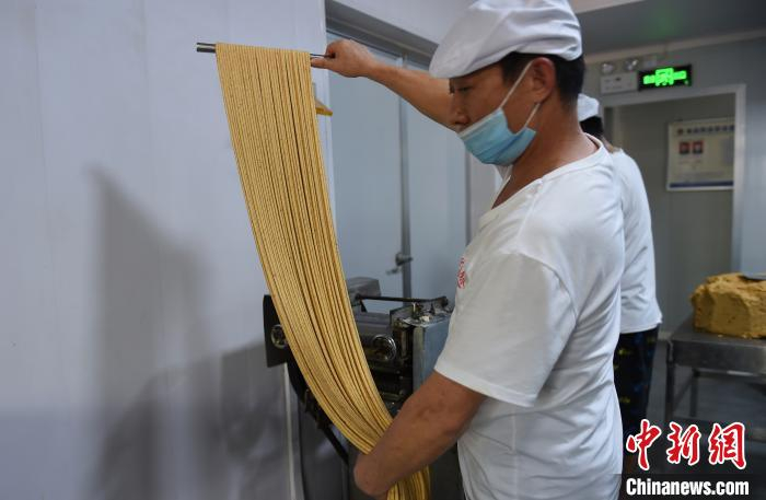 图为工人用现代化设备将面片切成粗细均匀的麻花绳。　周毅　摄