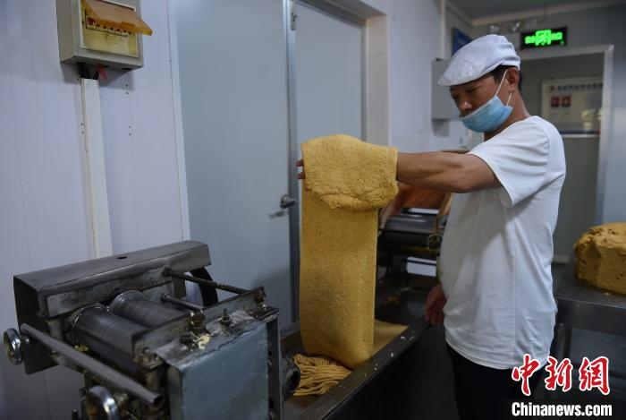 图为车间工人使用压面机代替人工擀面步骤，省时省力。　周毅　摄