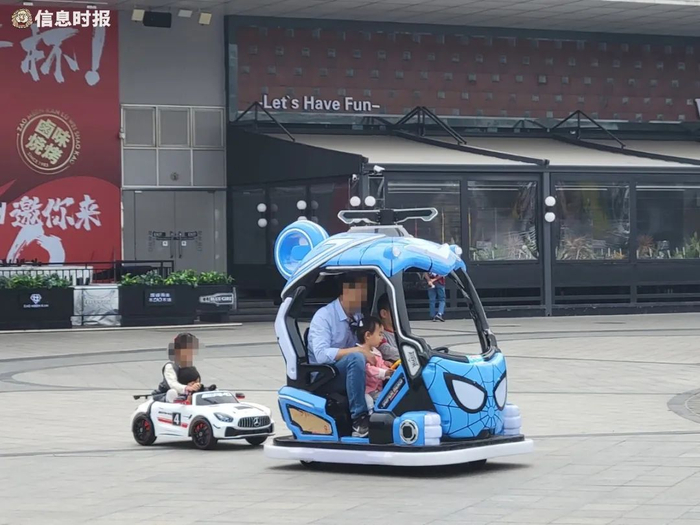 在五号停机坪，小型童车理论上只适合一人乘坐，却坐了两名孩子（信息时报记者 卢杰摄）