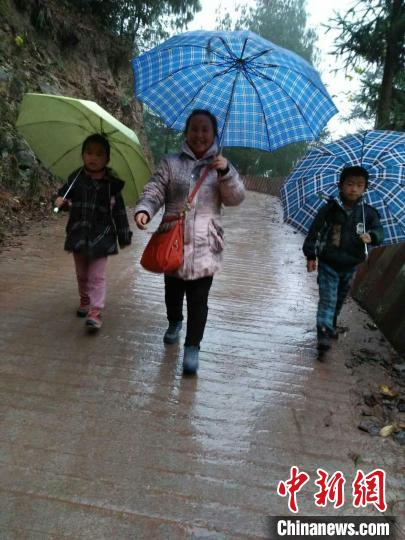 杨启分雨中携学生一同上学。　泸州市古蔺县委统战部供图