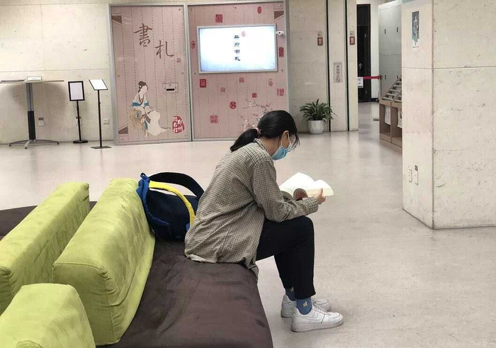7月20日晚，郑州图书馆，一个女孩儿捧着一本厚厚的书在读。图片来源：郑州图书馆订阅号