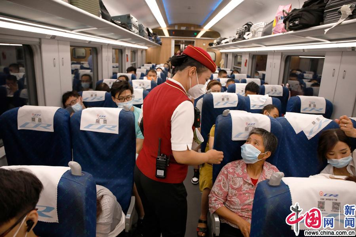 在D705次列车上，“心悦”班组列车长梁建正在为旅客服务。中国网记者 卢小凡 摄