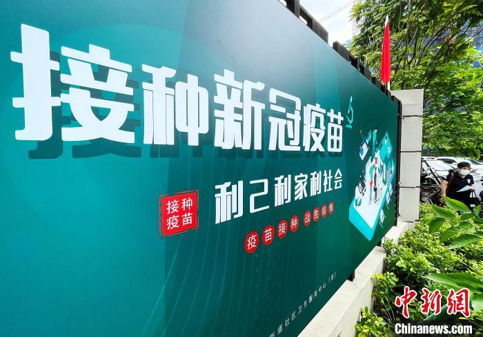 图为7月24日，市民从福州市仓山区金山街道社区卫生服务中心外，接种新冠疫苗宣传牌旁经过。　张斌 摄