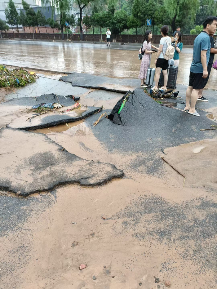 水退下后，路面堆满泥沙，沥青公路像破碎的塑胶跑道一样翻起。（受访者供图）