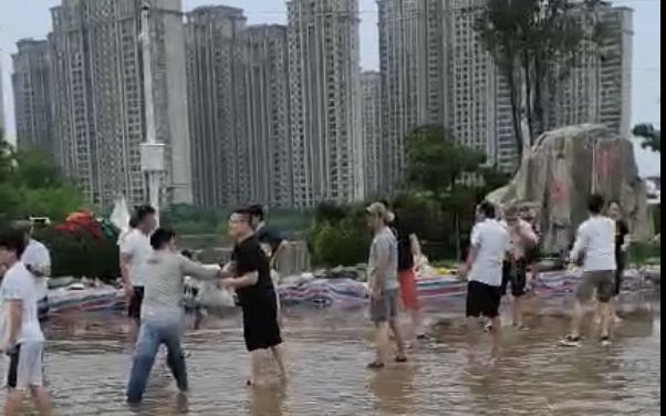 23日，志愿者们在水中传递沙袋、物资。受访者供图