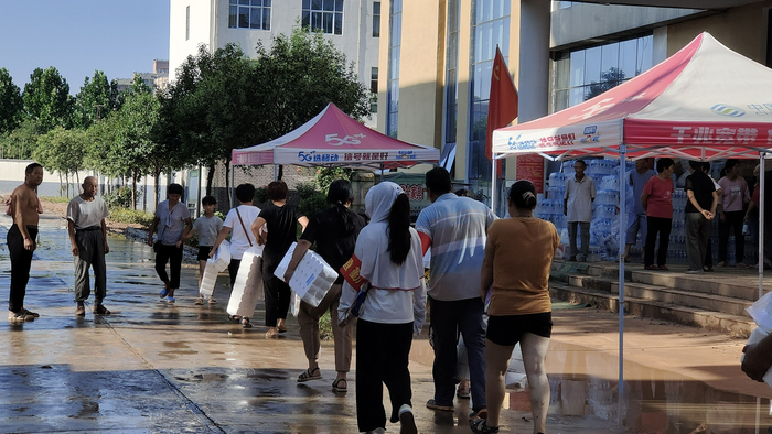 7月26日，淇县职业中专安置点内，村民们领走卫生纸等物资。新京报记者 刘瑞明 摄
